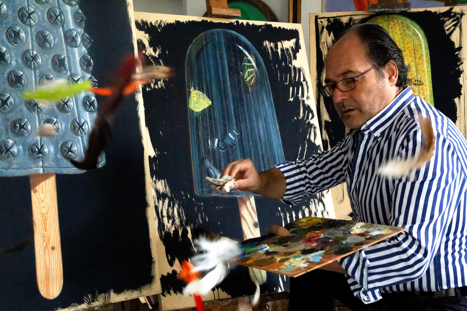 Salvatore Zito dipinge nell'atelier, tra le piume in volo